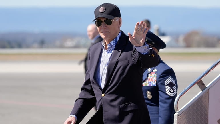 President Joe Biden waves as he arrives Air Force One,...