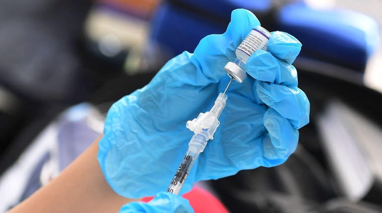An injection of the Pfizer COVID-19 vaccine is prepared at...