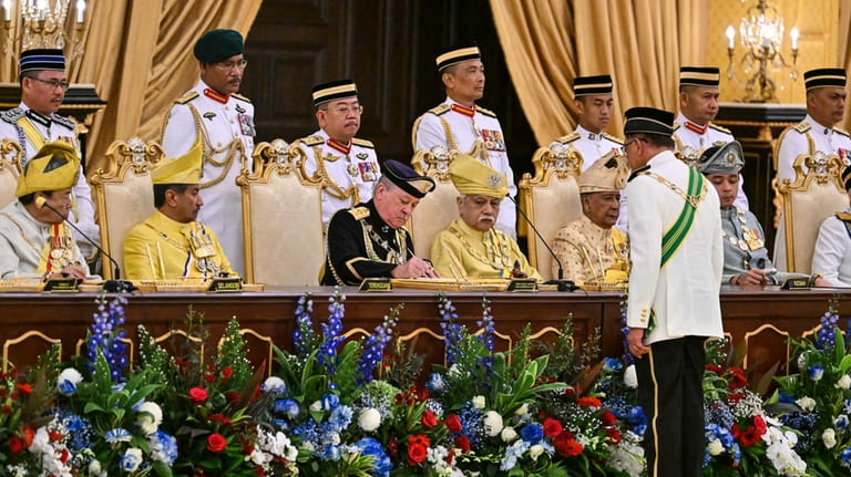 Sultan Ibrahim Sultan Iskandar, center left in front, signs documents...