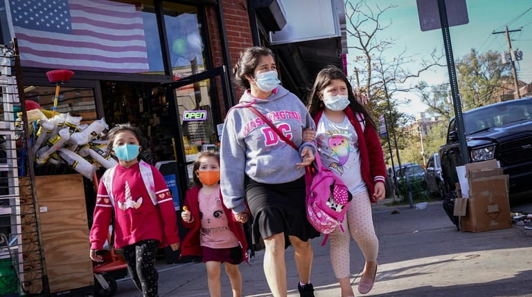 Pedestrians in masks pass a store Oct. 15 in the...