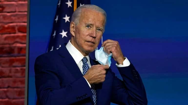 President-elect Joe Biden removes his face mask as he arrives...