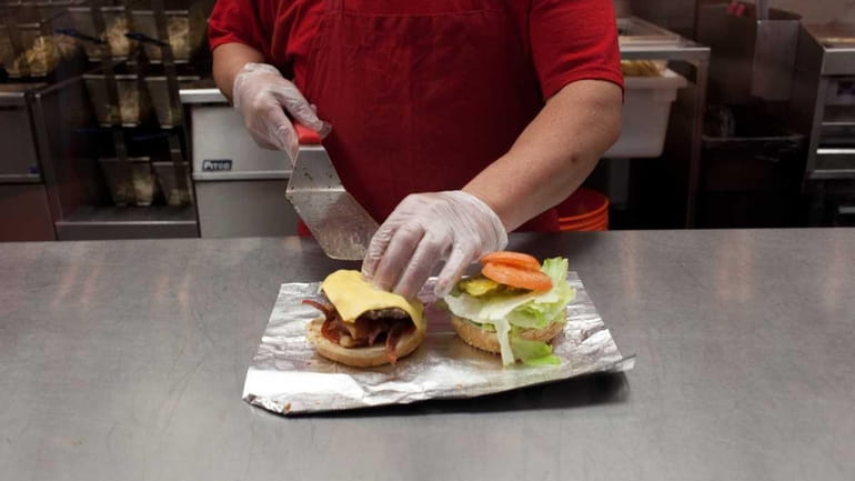 A bacon cheeseburger is assembled at the Five Guys Burgers...