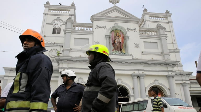 Sri Lankan firefighters stand in the area around St. Anthony's...