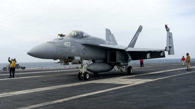 A F-18E parks on the flight deck of a USS...