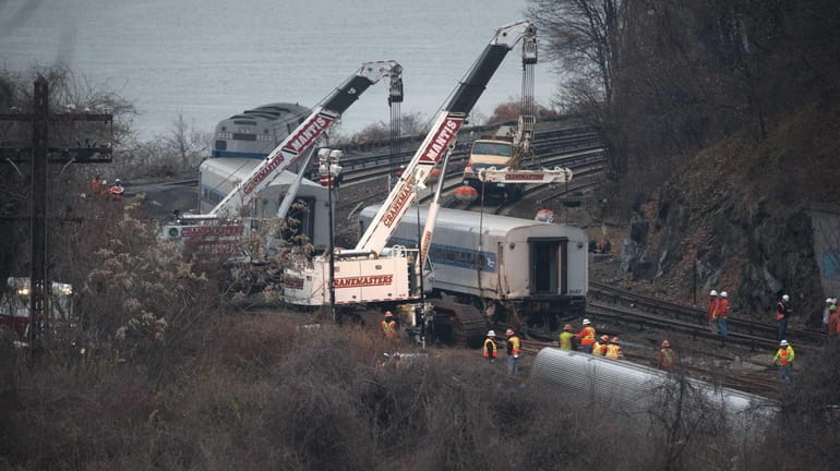 Cranes are used to right derailed Metro-North train cars at...