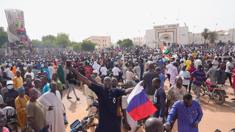 Nigeriens, some holding Russian flags, participate in a march called...