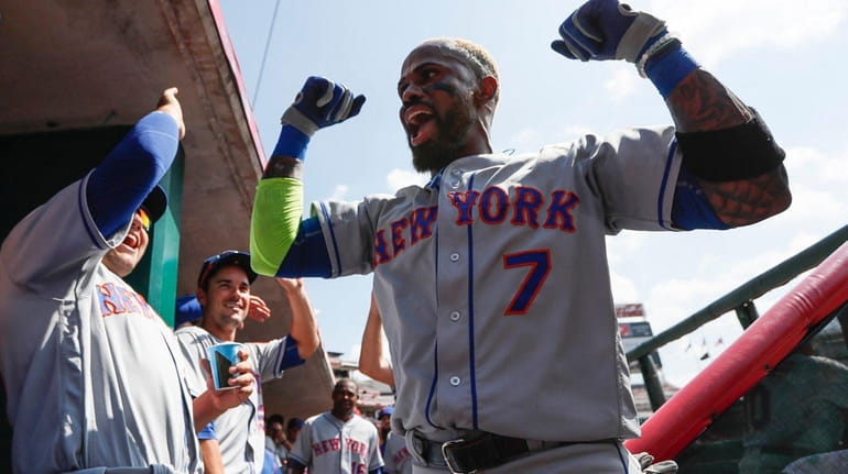New York Mets' Jose Reyes celebrates in the dugout after...