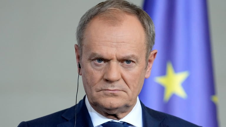 Poland's Prime Minister Donald Tusk listens to the media in...