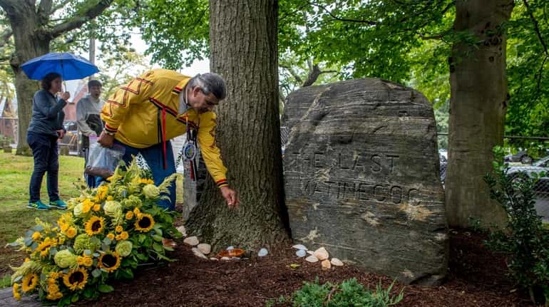 Unkechaug Nation chief Harry Wallace places tobacco on the grave...