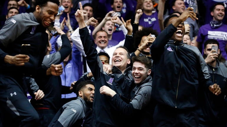 Northwestern coach Chris Collins, center, and players react while watching...