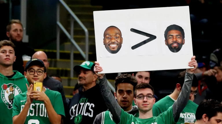 A fan holds a sign with photos of Kemba Walker...