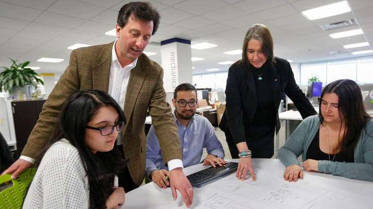 H2M Architects and Engineers CEO Rich Humann, standing, confers with staff, from...