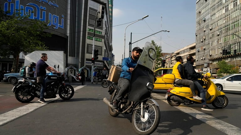 Motorbikes cross an intersection in downtown Tehran, Iran, Sunday, April...