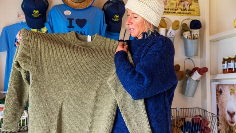 Holly Browder holds a sweater in her store made with...