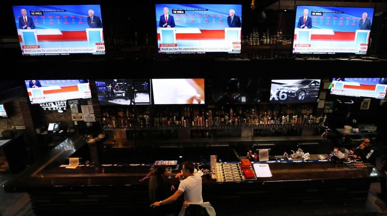 Patrons watch Sunday night's Democratic debate at a nearly empty...