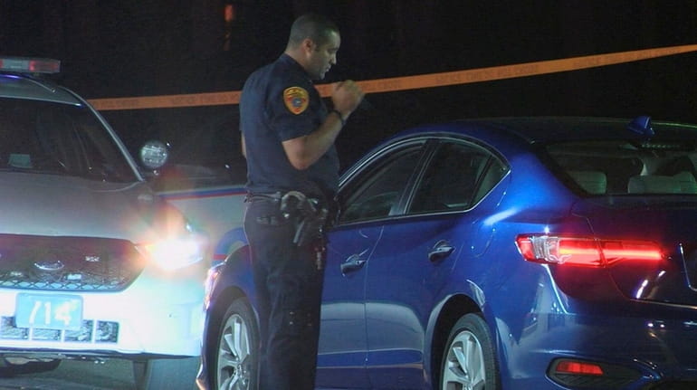 A Suffolk County police officer looks over a vehicle after...