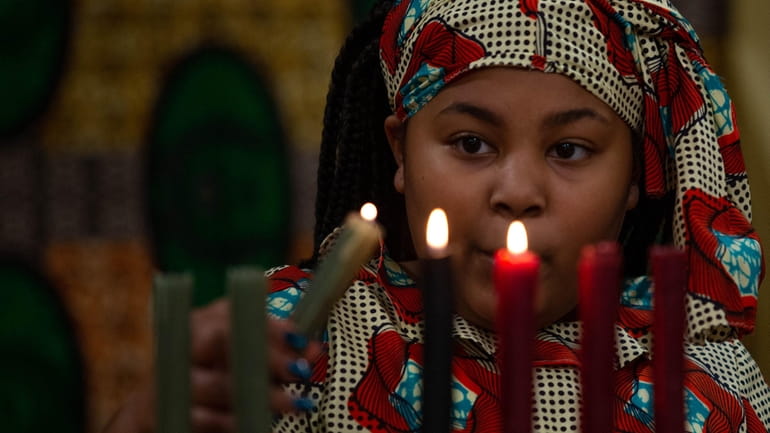 Hannah Galley lights the seven candles of the Kinara, which...