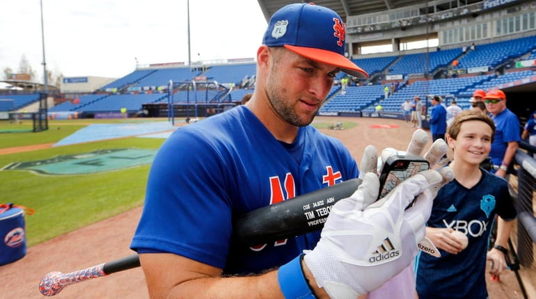 New York Mets' Tim Tebow helps a fan take a...