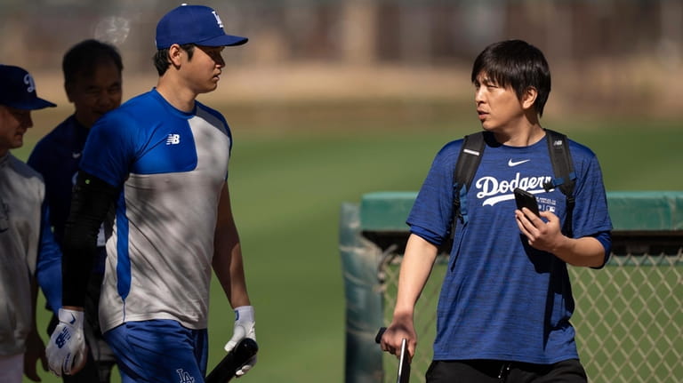 Los Angeles Dodgers' Shohei Ohtani walks with interpreter Ippei Mizuhara...