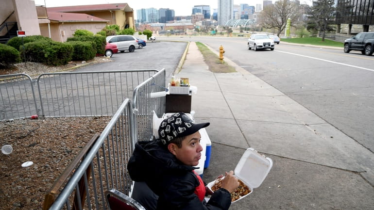 Lincoln Montero eats outside a motel designated for migrants after...