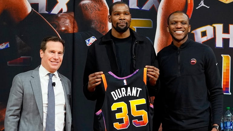 Suns forward Kevin Durant, center, holds his jersey after being...