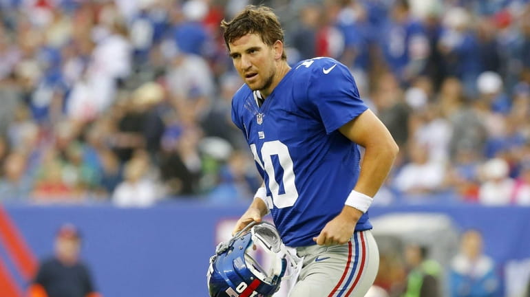 Giants quarterback Eli Manning walks to the sidelines after throwing...