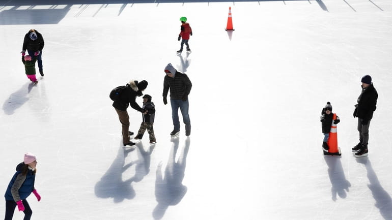 Ice skaters enjoy a sunny cold day on the outdoor...