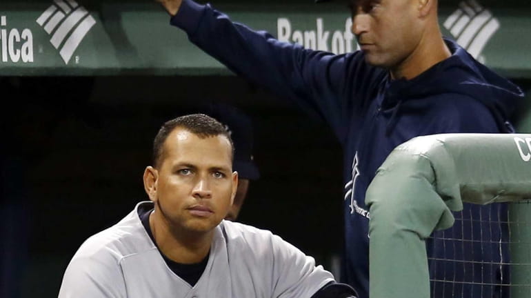Yankees' Alex Rodriguez sits in the dugout as Derek Jeter...