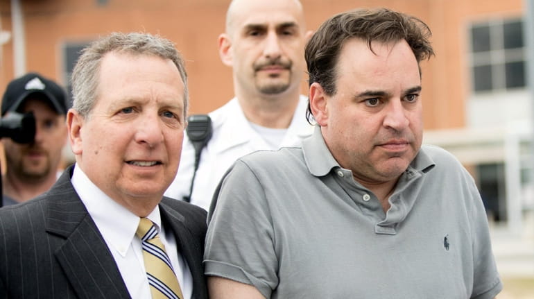 Suffolk County District Judge Robert Cicale, right, is escorted out...