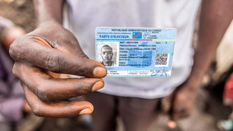 Elisha Manishimwe holds his voter's card in the Kanyaruchinya displaced...