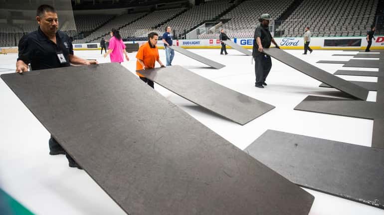 Crews cover the ice at American Airlines Center in Dallas,...