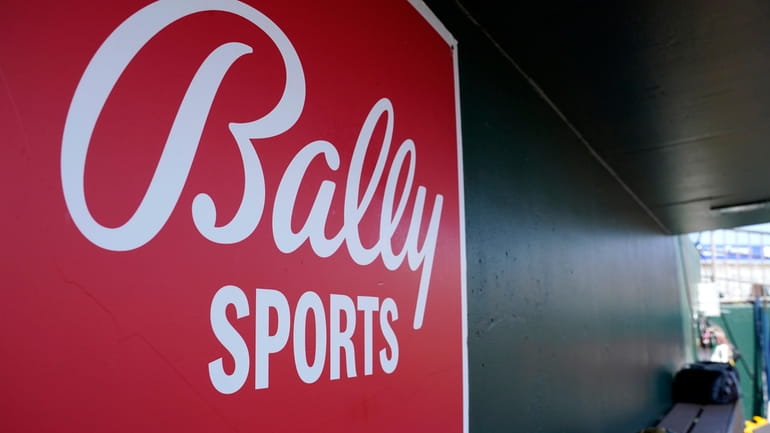 A Bally Sports logo is on a dugout wall during...