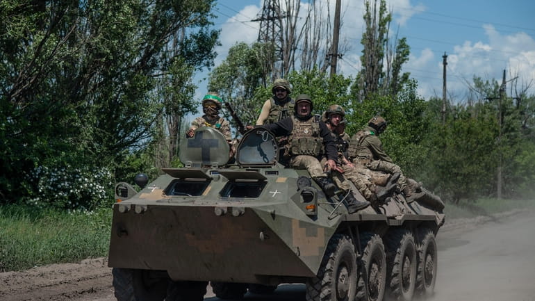 Ukrainian soldiers ride an APC on the frontline near Bakhmut,...