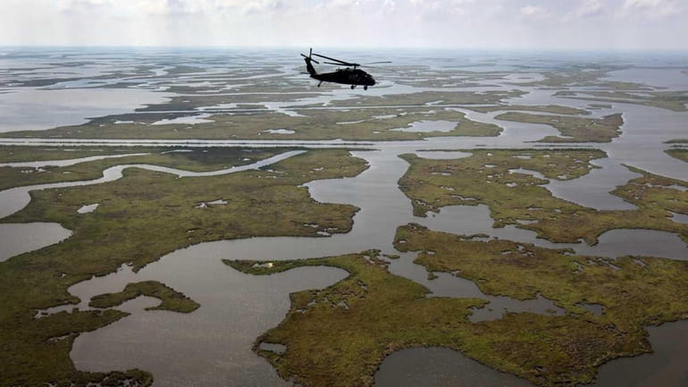 A Louisiana National Guard blackhawk flies over marshland on April...