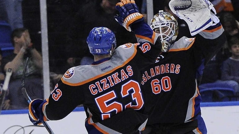 Islanders goalie Kevin Poulin is congratulated by Casey Cizikas after...