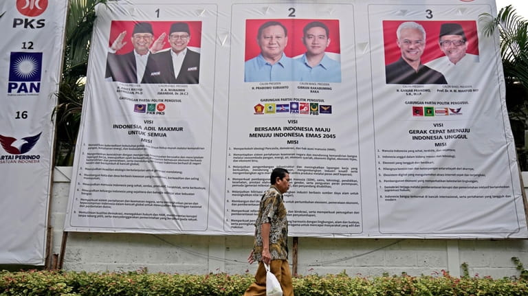 A man walks past an election banner introducing presidential candidates,...