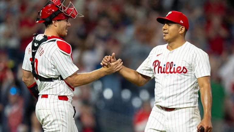 Philadelphia Phillies starting pitcher Ranger Suarez, right, celebrates the win...