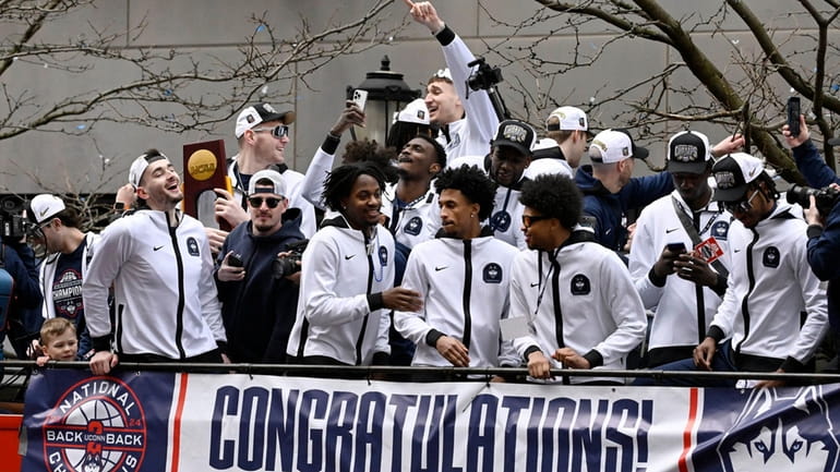 UConn players ride on a double decker bus during a...