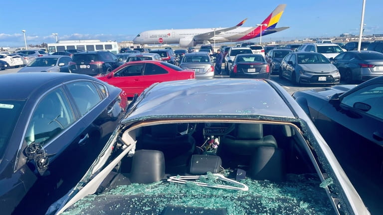 Damaged cars are seen in an on-airport employee parking lot...