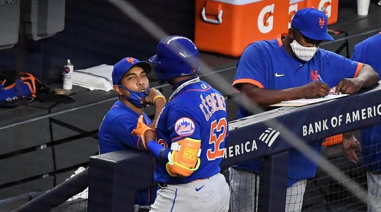 Mets manager Luis Rojas talks to Yoenis Cespedes as he returns...