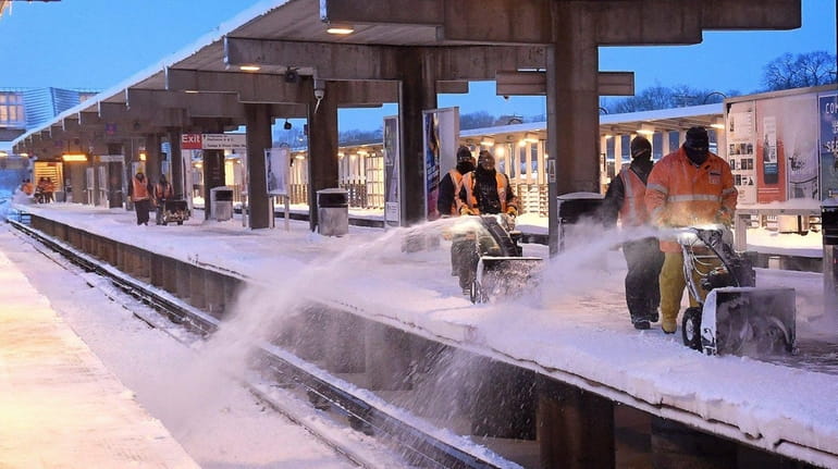 Long Island Rail Road personnel work to clear snow from...