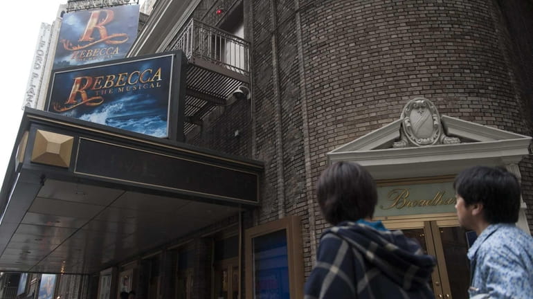 People walk by advertisements for the the cancelled musical, "Rebecca,"...