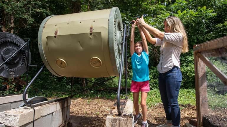 Catherine Williams and her daughter Brooke turn the compost tumbler...