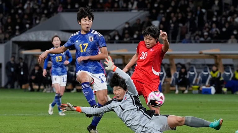 Japan's Kiko Seike, left, kicks the ball in an attempt...