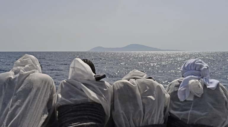 TOPSHOT - Migrants look at the Pantelleria island from the...