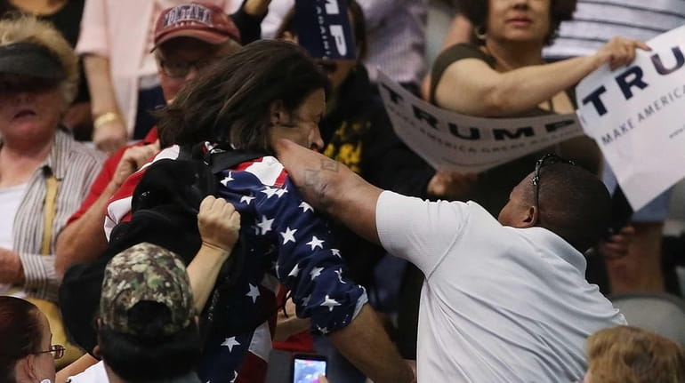Trump protester Bryan Sanders, center left, is punched by a...