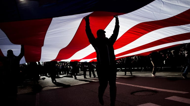 People carry an American flag as they march in the...