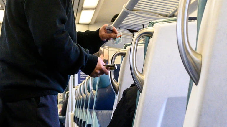 A conductor punches tickets on an LIRR train.