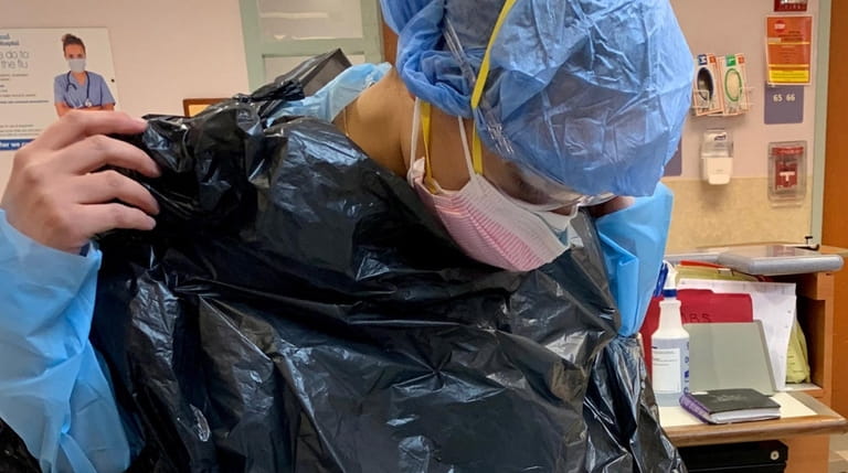 Nurse Michelle Farid wears a contractor bag over her gown...
