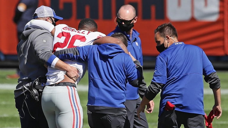 Saquon Barkley of the Giants is helped off the field with...